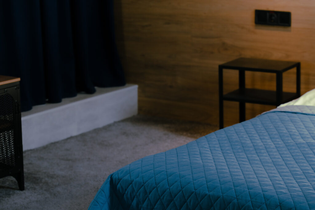 pleasant low light warm from electric lamp in bed room empty evening cozy space narrow focus indoor view with sheet floor and walls